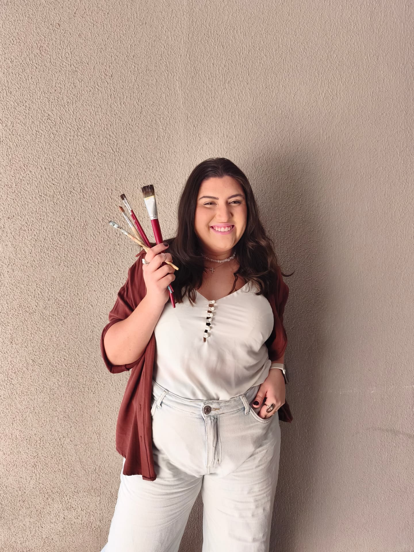 Isa, artista do ateliê Isa Arte Sacra, segurando pincéis
